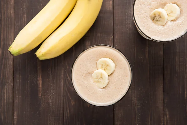 Batido de banana de tiro superior na mesa de madeira — Fotografia de Stock