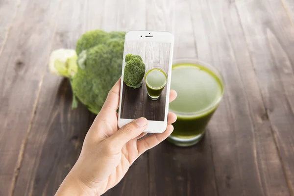 Taking photo of broccoli juice on wood table. — Stock Photo, Image