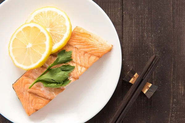 Von oben gegrillter Lachs mit Zitrone auf Teller. — Stockfoto