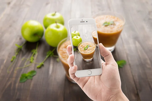 Tirando foto de maçãs verdes smoothie no fundo de madeira — Fotografia de Stock