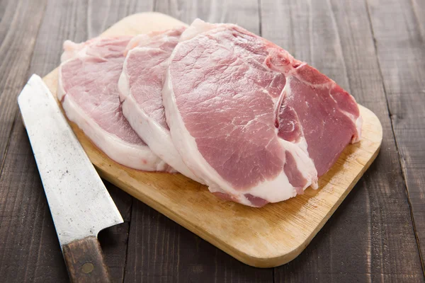 Raw pork chop steak and cleaver on wooden background — Stock Photo, Image