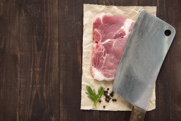 Carne di maiale cruda costata e mannaia su sfondo di legno — Foto Stock