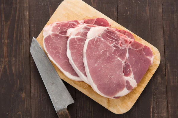 Raw pork chop steak and cleaver on wooden background Royalty Free Stock Photos