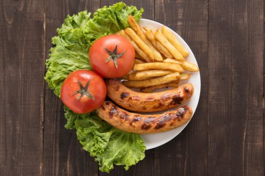 Izgara sosis ve sebze ahşap arka plan üzerinde patates kızartması ile