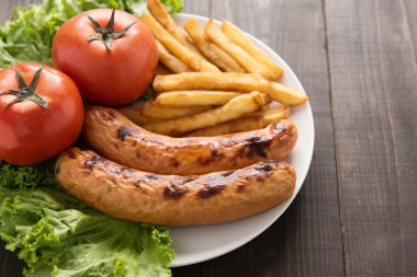 Izgara sosis ve sebze ahşap arka plan üzerinde patates kızartması ile