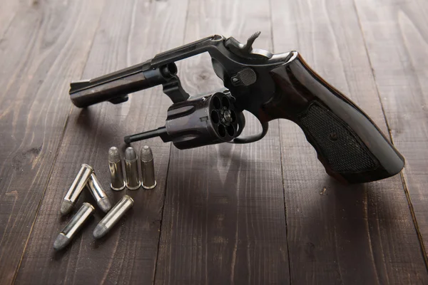 Pistola revolver nera con proiettili isolati su sfondo di legno — Foto Stock