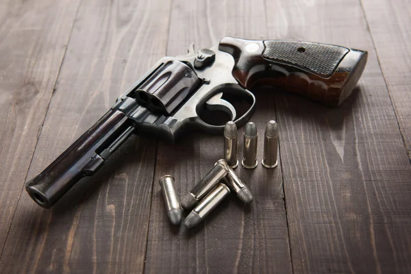 Zwarte revolver pistool met opsommingstekens geïsoleerd op houten achtergrond — Stockfoto