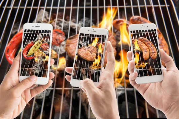 Amigos usando teléfonos inteligentes para tomar fotos de salchichas y cerdo — Foto de Stock