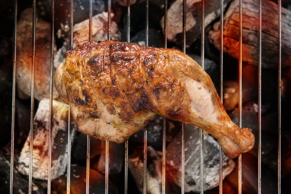 Muslo de pollo a la parrilla sobre llamas en una barbacoa . — Foto de Stock