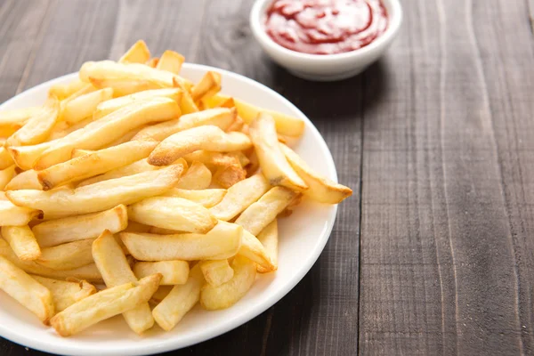 Pommes frites med ketchup på trä bakgrund — Stockfoto