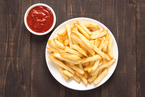 French fries with ketchup on wooden background
