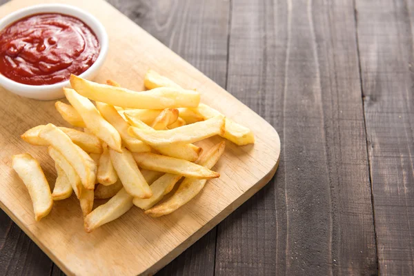 Batatas fritas com ketchup em fundo de madeira. — Fotografia de Stock