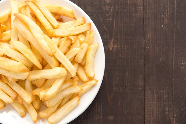 Pommes frites på vit maträtt på trä bakgrund — Stockfoto
