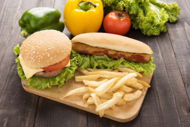 Hamburgers, french fries and vegetable on the wooden background.