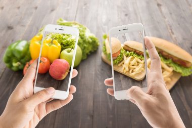 Friends using smartphones to take photos with contrasting food.