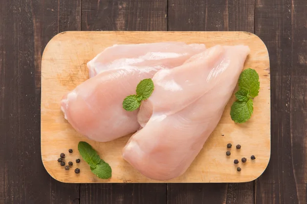 Filetti di petto di pollo crudo su sfondo di legno — Foto Stock