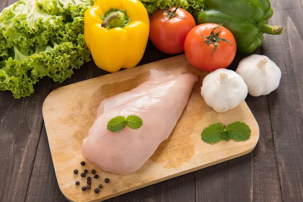 Rohe Hühnerbrustfilets und Gemüse auf hölzernem Hintergrund. — Stockfoto
