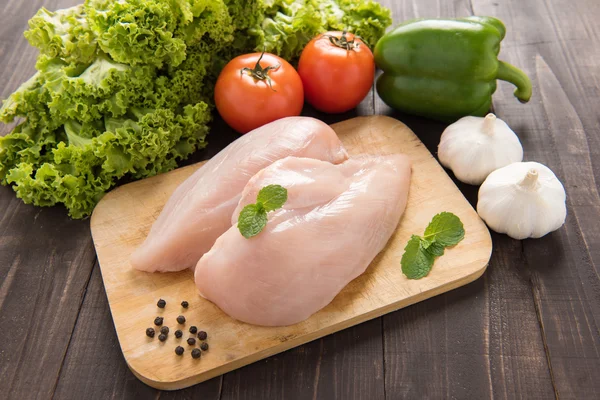 Сырое филе куриной грудки и овощи на деревянном фоне . — стоковое фото