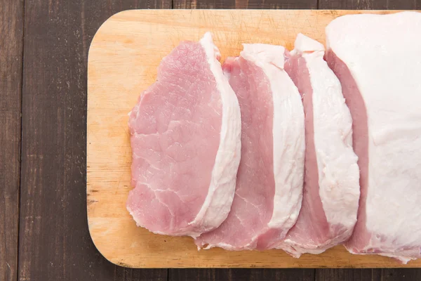 Cerdo crudo en tabla de cortar sobre fondo de madera . — Foto de Stock