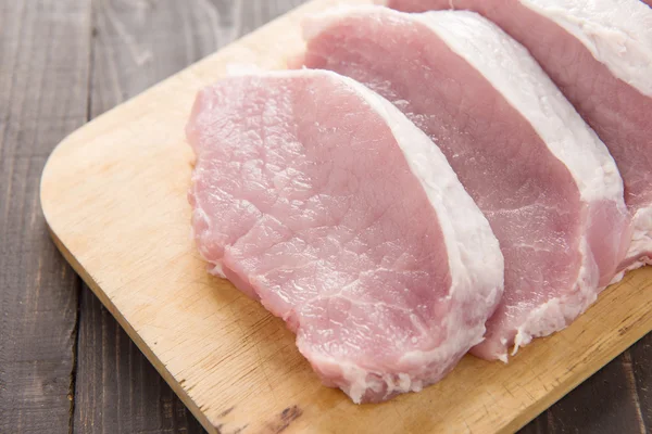 Raw pork on cutting board on wooden background. Stock Photo