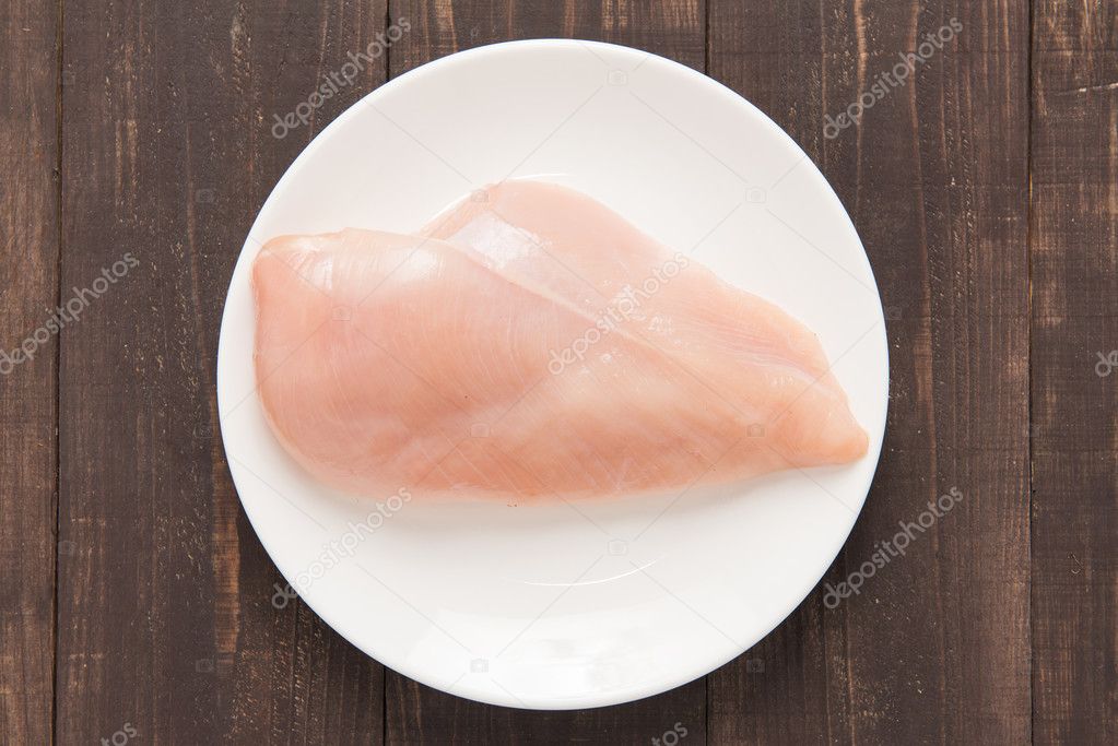 Raw chicken breast fillets on white dish.
