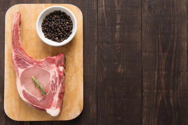 Chuletas de cerdo frescas y pimienta sobre fondo de madera — Foto de Stock