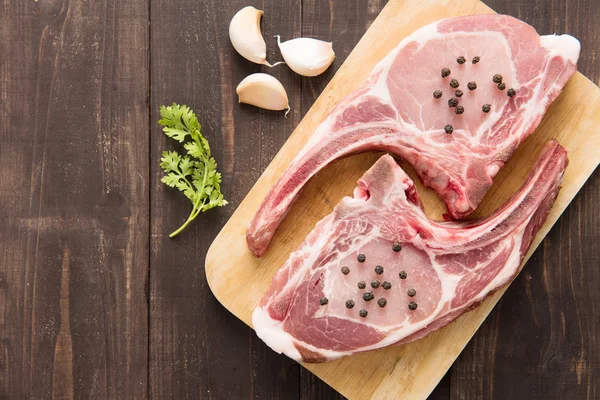 Frische rohe Schweinekoteletts auf Holzgrund. — Stockfoto