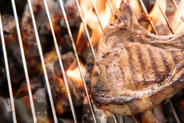 Grilled pork steaks over flames on the grill. — Stock Photo, Image