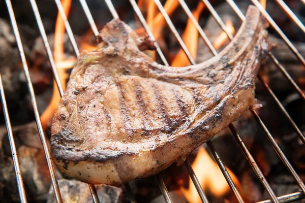 Grilled pork steaks over flames on the grill. — Stock Photo, Image