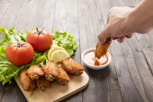 Hand dunk chicken hot wings in dipping sauce on wooden. — 图库照片