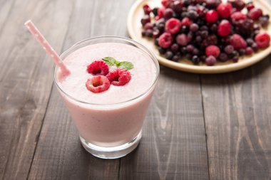Raspberry smoothie and fresh raspberry and blueberry on wooden b
