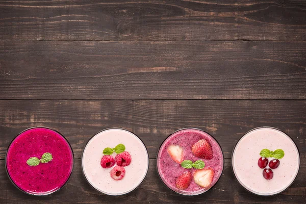 Set of fruit smoothie in glasses on wooden background.