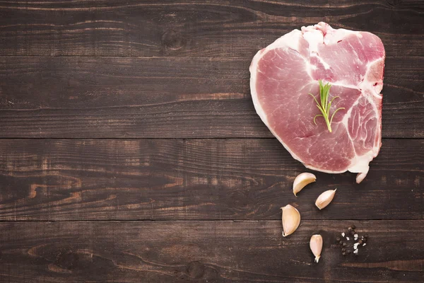 Horní pohled syrové vepřová kotleta steak a česnek, pepř na dřevěné pozadí — Stock fotografie