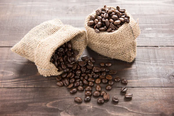 Koffie bonen in een zak op houten achtergrond — Stockfoto