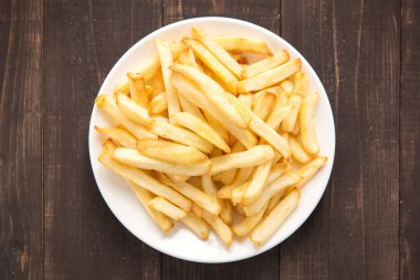 Ahşap arka planda beyaz tabakta patates kızartması.