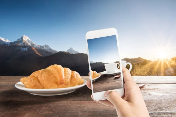 Taking photo of fresh baked croissants and coffee on a wooden ta — Stock Photo, Image