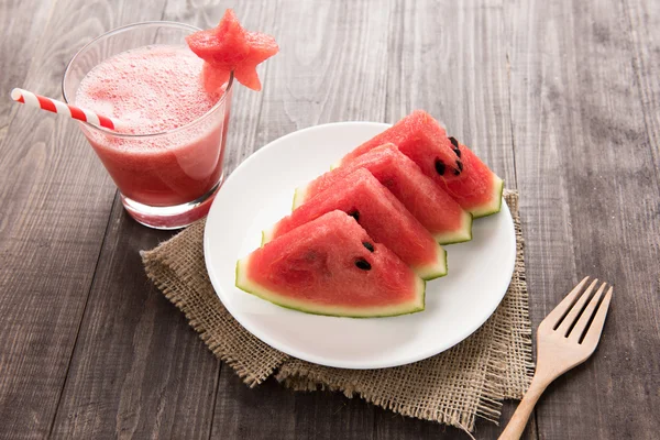 Gezonde segment watermeloen met watermeloen smoothie op een houten rug — Stockfoto