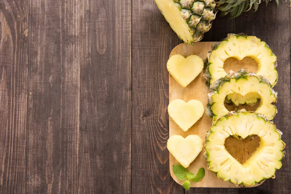 Ahşap bac üzerinde kalp şeklinde bir kesim ile ananas dilimleri — Stok fotoğraf