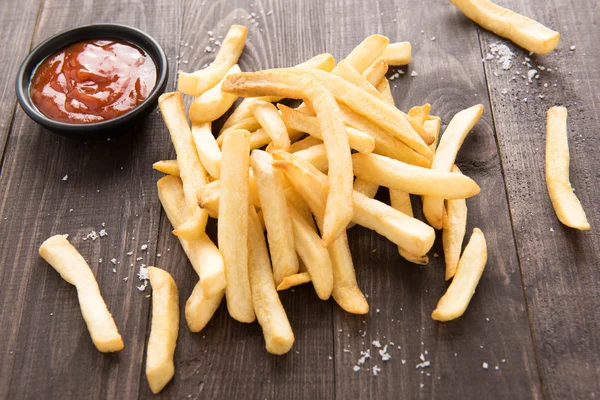 Batatas fritas com ketchup em fundo de madeira — Fotografia de Stock