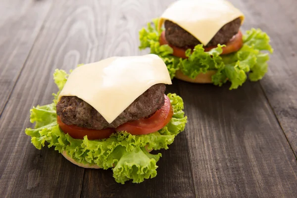 Hamburger s hlávkovým salátem a sýrem na dřevěný stůl — Stock fotografie