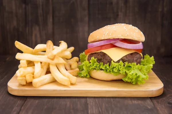 Cheeseburger s hranolky na dřevěné pozadí — Stock fotografie