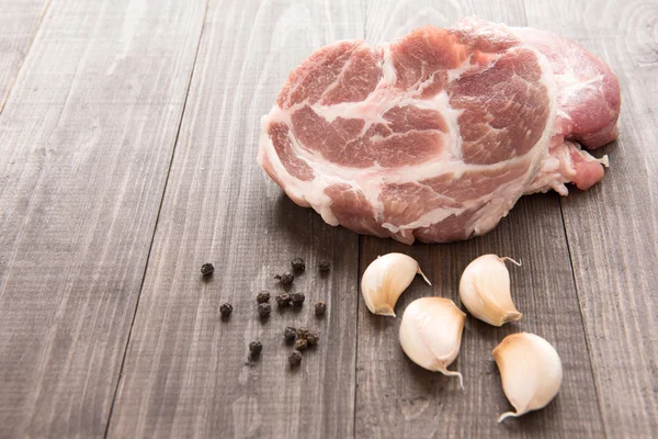 Carne fresca cruda e aglio, pepe su fondo di legno — Foto Stock