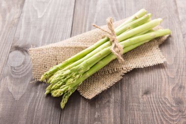 Rustik ahşap bir masa üzerinde taze yeşil kuşkonmaz demet