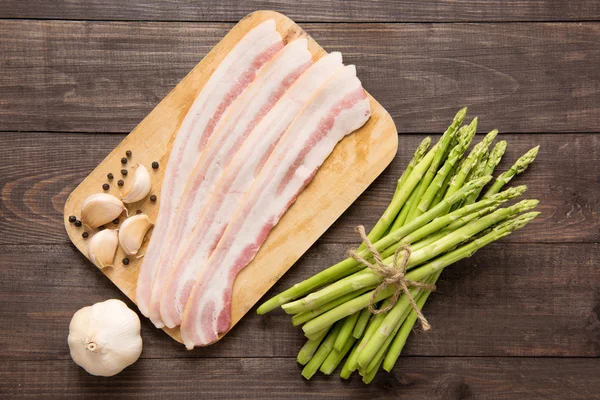 Smoked bacon with fresh asparagus on wooden background — Stock Photo, Image