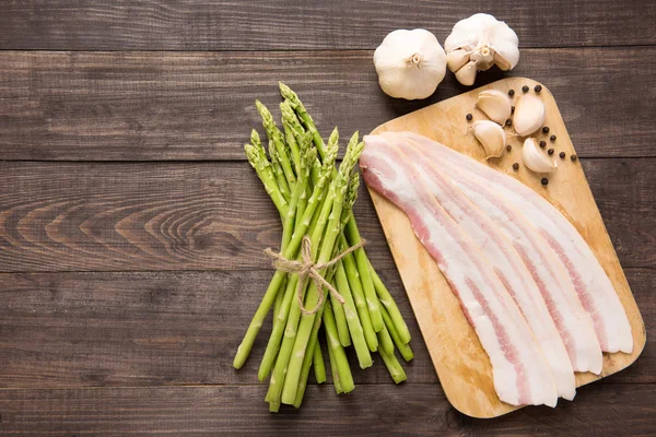 Panceta ahumada con espárragos frescos sobre fondo de madera — Foto de Stock