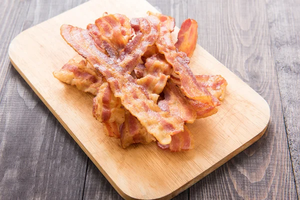 Fried bacon strips on the wooden board — Stock Photo, Image