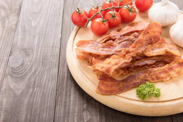 Fried bacon, tomato and garlic on the wooden board — Stock Photo, Image