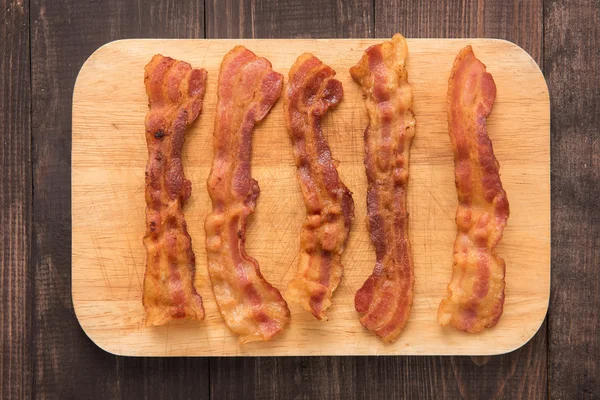 Fried bacon strips on the wooden board — Stock Photo, Image