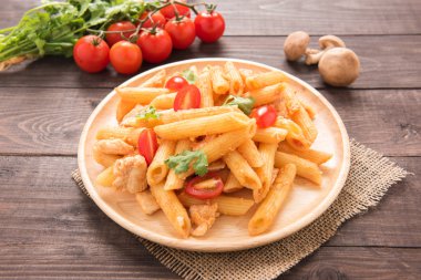 Ahşap bir masa üzerinde tavuk domates soslu Penne makarna