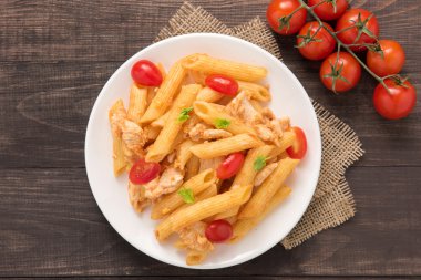 Ahşap bir masa üzerinde tavuk domates soslu Penne makarna